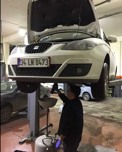 Lifte alınmış bir Seat aracın altında yağ boşaltma işlemi