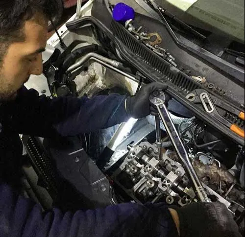 Ustamız üst kapağı açılmış bir motorun supap mekanizması üzerinde çalışıyor
